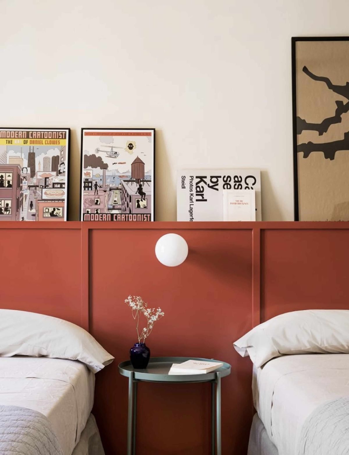 Twin room with terracotta panelled headboard, framed prints and a globe wall light.